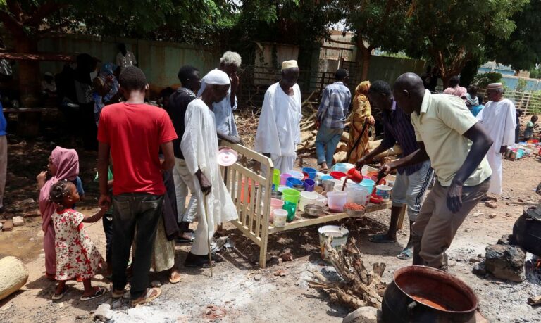 FILE PHOTO: People wait to get food distributed by volunteers in Omdurman. REUTERS/El Tayeb Siddig/File Photo