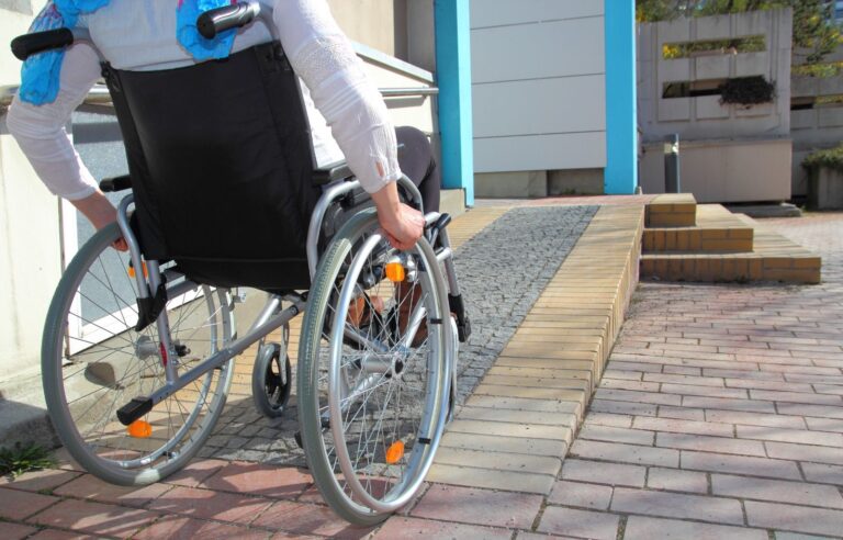 Imagem de um homem em uma cadeira de rodas, subindo uma rampa.
