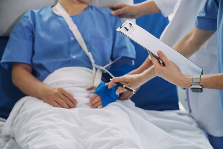 Imagem de uma paciente ortopédica sentada em uma maca, sendo atendida por um profissional de saúde.