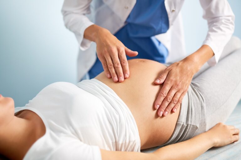 Imagem de uma mulher grávida sendo examinada por uma profissional de saúde.