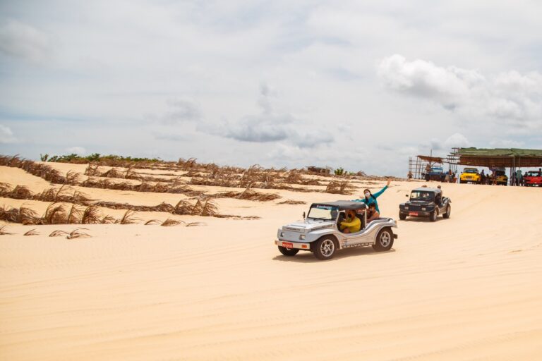 Imagem de buggy com turistas fazendo passeio sobre uma duna.