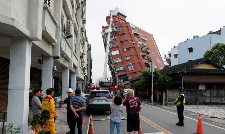 People look on as workers carry out operations while on an elevated platform of a firefighting truck at the site where a building collapsed, following the earthquake, in Hualien, Taiwan April 4, 2024. REUTERS/Carlos Garcia Rawlins