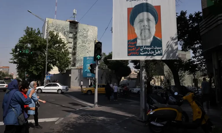 People stand near a banner with a picture of the late Iran's President Ebrahim Raisi on a street in Tehran, Iran May 20, 2024. Majid Asgaripour/WANA (West Asia News Agency) via REUTERS ATTENTION EDITORS - THIS PICTURE WAS PROVIDED BY A THIRD PARTY