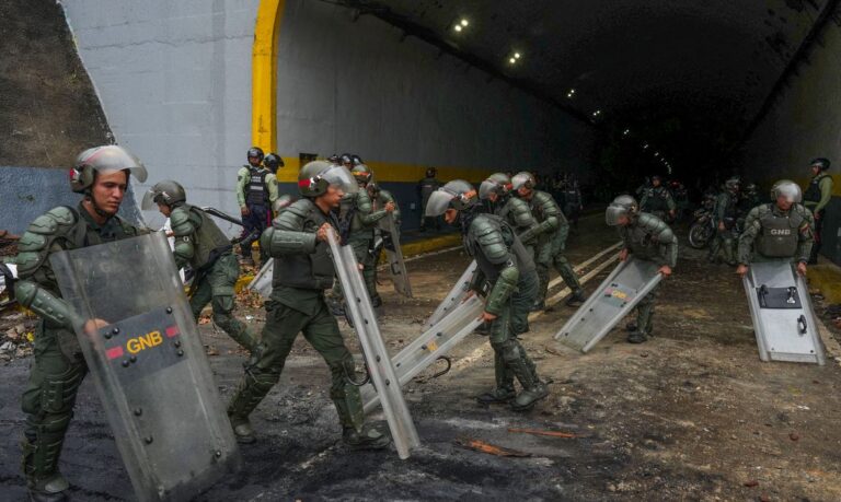 Members of the Bolivarian National Guard of Venezuela use their shields to clean an avenue after a protest from supporters of Venezuelan opposition following the announcement by the National Electoral Council that Venezuela's President Nicolas Maduro won the presidential election, in Caracas, Venezuela July 29, 2024. REUTERS/Alexandre Meneghini