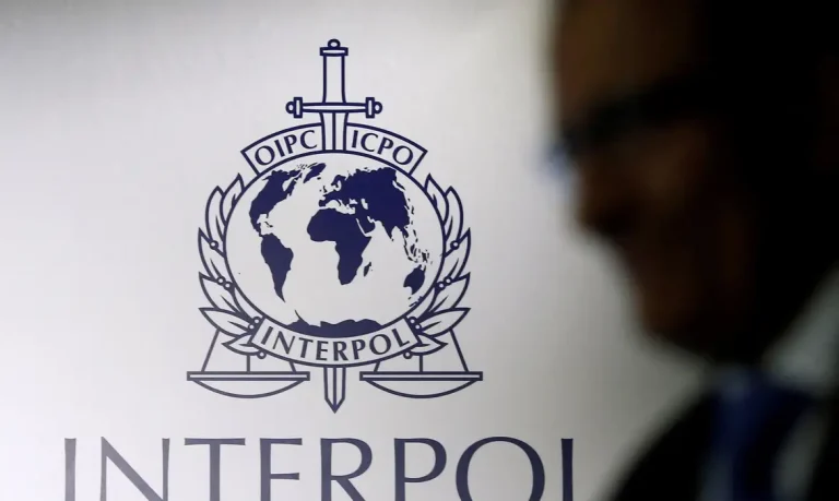 FILE PHOTO: A man passes an Interpol logo during the handing over ceremony of the new premises for Interpol's Global Complex for Innovation, a research and development facility, in Singapore September 30, 2014. REUTERS/Edgar Su//File Photo