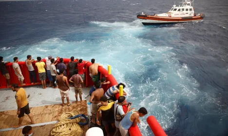 .Pessoas a bordo do barco de resgate da ONG Proactiva Open Arms Uno olham para o barco da guarda costeira indo para a ilha de Lampedusa, no mar Mediterrâneo central, Itália.
19/08/2022
REUTERS/Juan Medina/Foto de arquivo