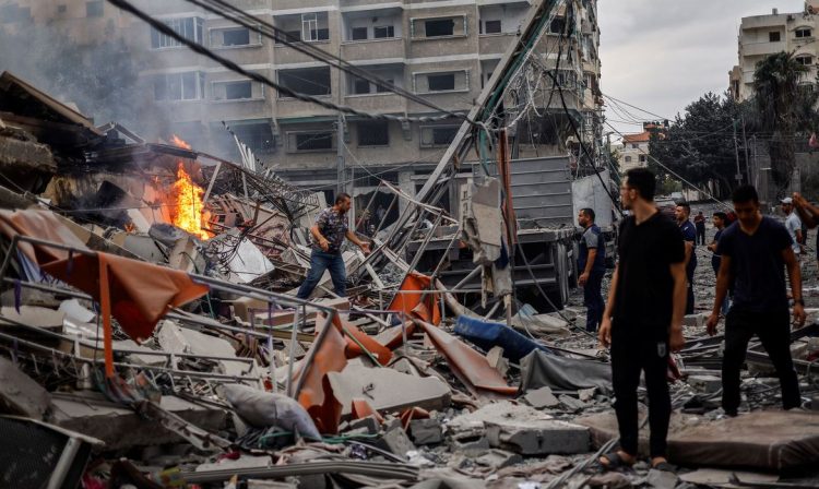 Palestinos caminham em meio a destroços de prédios destruídos por Israel em Gaza