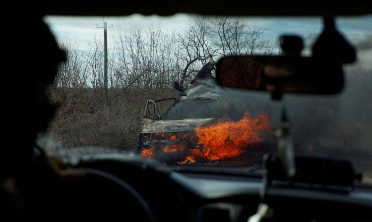 FILE PHOTO: Ukrainian servicemen move past a burning car hit by a kamikaze drone outside the front line town of Avdiivka, amid Russia's attack on Ukraine, in Donetsk region, Ukraine November 8, 2023. Radio Free Europe/Radio Liberty/Serhii Nuzhnenko via REUTERS/File Photo