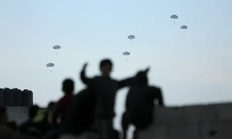 People watch as U.S. military carries out its first aid drop over Gaza, amid the ongoing the conflict between Israel and the Palestinian Islamist group Hamas, in Gaza City, March 2, 2024. REUTERS/Kosay Al Nemer      TPX IMAGES OF THE DAY