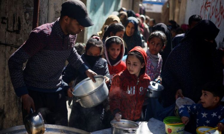 CRIANÇAS FOME GAZA - Palestinian children wait to receive food cooked by a charity kitchen amid shortages of food supplies, as the ongoing conflict between Israel and the Palestinian Islamist group Hamas continues, in Rafah, in the southern Gaza Strip, March 5, 2024. REUTERS/Mohammed Salem