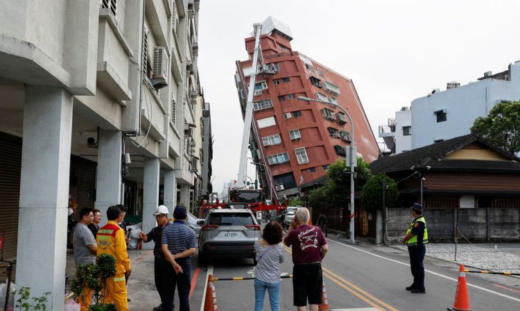 People look on as workers carry out operations while on an elevated platform of a firefighting truck at the site where a building collapsed, following the earthquake, in Hualien, Taiwan April 4, 2024. REUTERS/Carlos Garcia Rawlins