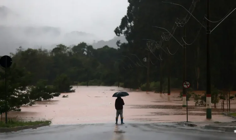 A man stands in front of flooded road near the Taquari River during heavy rains in the city of Encantado in Rio Grande do Sul, Brazil, May 1, 2024. REUTERS/Diego Vara