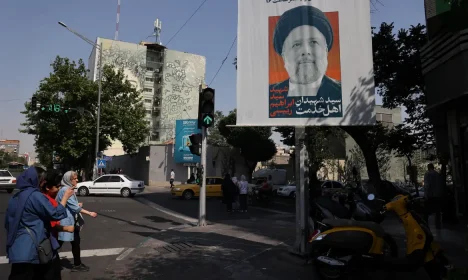 People stand near a banner with a picture of the late Iran's President Ebrahim Raisi on a street in Tehran, Iran May 20, 2024. Majid Asgaripour/WANA (West Asia News Agency) via REUTERS ATTENTION EDITORS - THIS PICTURE WAS PROVIDED BY A THIRD PARTY