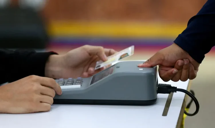 A woman is checked with a fingerprint identity registration device at a polling station in the Liceo Andres Bello during Venezuela's presidential election, in Caracas, Venezuela, July 28, 2024. REUTERS/Fausto Torrealba