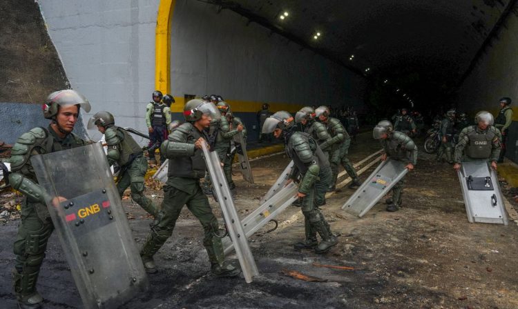 Members of the Bolivarian National Guard of Venezuela use their shields to clean an avenue after a protest from supporters of Venezuelan opposition following the announcement by the National Electoral Council that Venezuela's President Nicolas Maduro won the presidential election, in Caracas, Venezuela July 29, 2024. REUTERS/Alexandre Meneghini