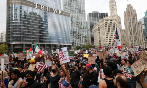 Demonstrators hold signs in front of Trump International Hotel and Tower, as they gather for a