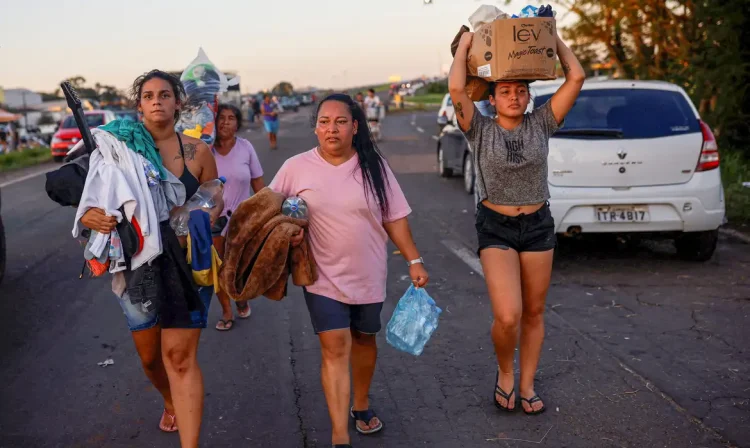 People walk carrying donated items in Eldorado do Sul, in Rio Grande do Sul, Brazil, May 6, 2024. REUTERS/Amanda Perobelli