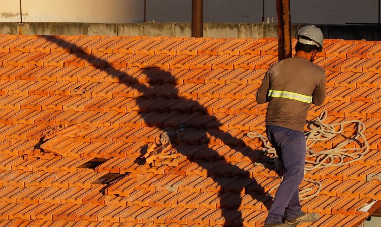 Operários reformam telhado de imóvel em obras no Centro do Rio.