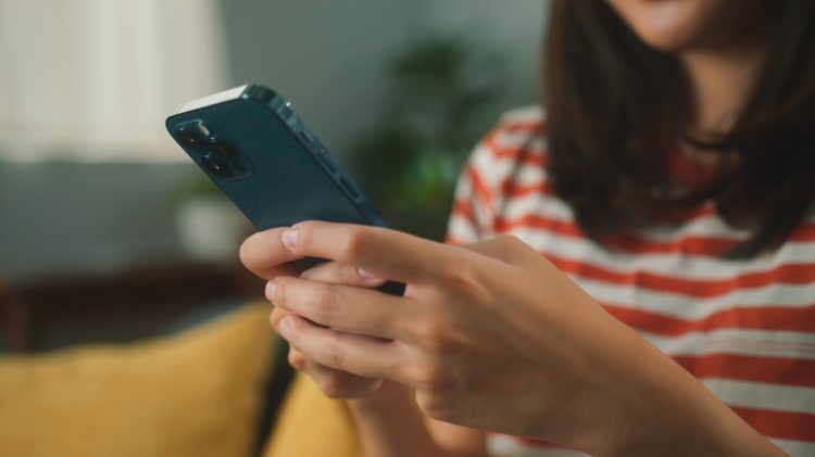 Imagen das maos de uma mulher usando o telefone para digitar