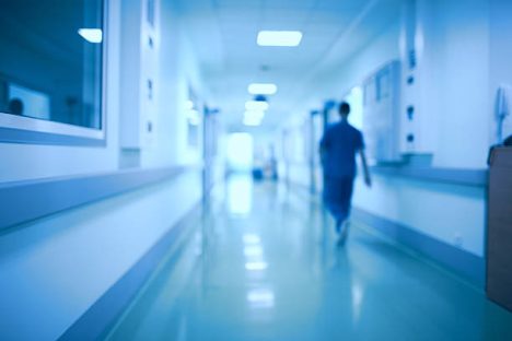 Imagem de coredor de hospital com uma uma pessoa andando