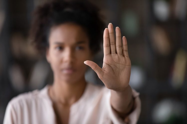 imagem de mulher desfocada com a mão levantada em sinal de pare