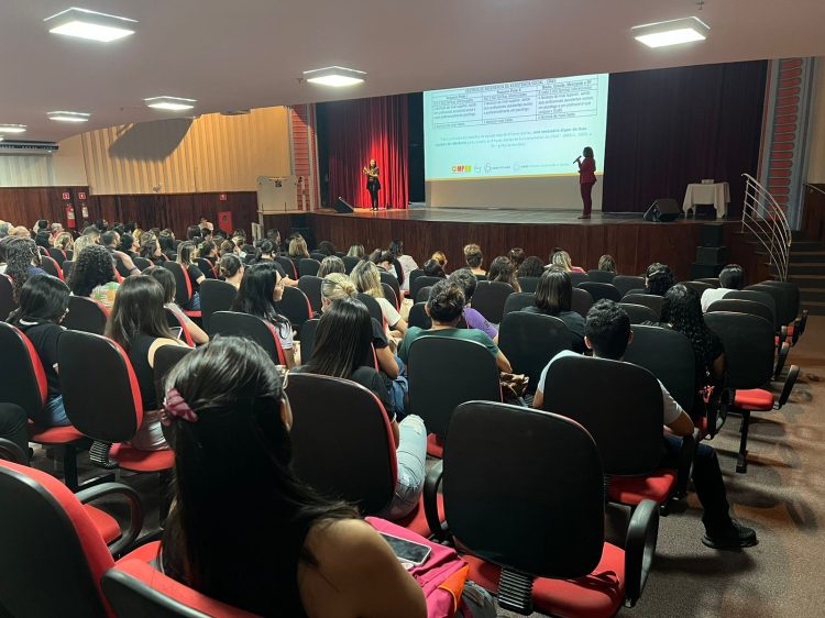 Imagem de um auditório repleto de pessoas assistindo a uma palestra.