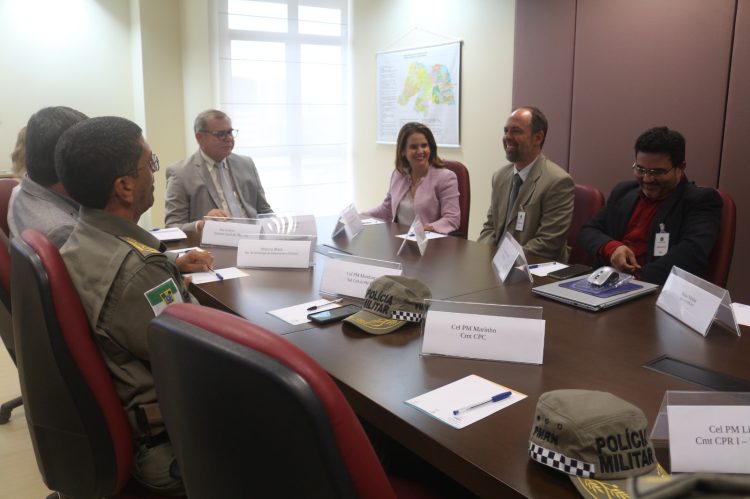 Imagem de uma reunião, em uma sala fechada, com sete pessoas sentadas ao redor de uma mesa.