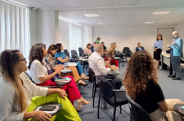 Imagem de várias pessoas sentadas, em uma sala assistindo a uma palestra.