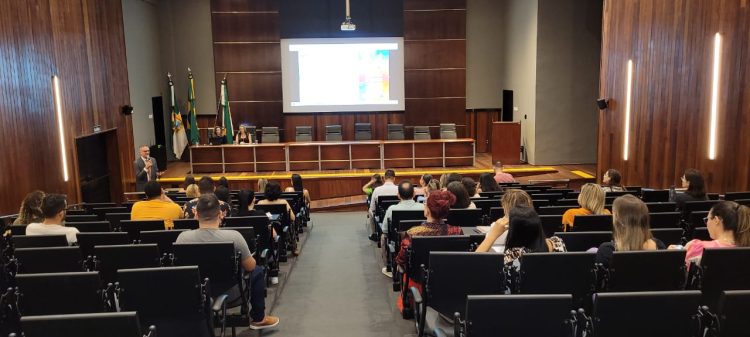 Imagem de um auditório com algumas pessoas sentadas, participando de uma reunião.