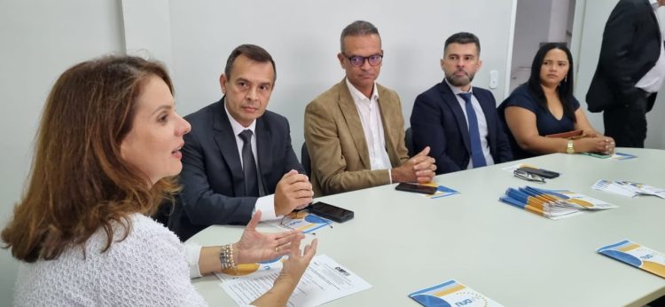 Imagem da procuradora-geral de Justiça, Elaine Cardoso, e de outras autoridades, todos sentados à mesa, durante a inauguração do NUAVV.