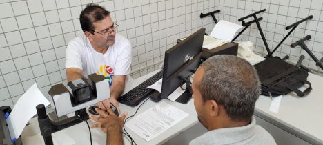 Imagem de uma pessoa em situação de rua tendo as digitais colhidas para a emissão de RG